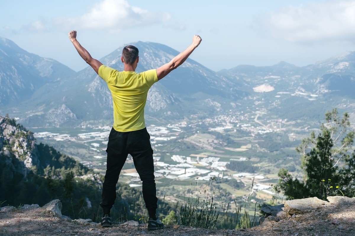 Un homme en haut d'une montagne, célébrant les bras dans les airs!