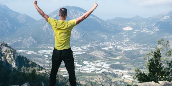 A man at the top of the mountain, arms wide open, unleashed!