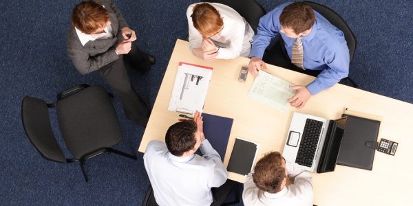 Business people working around a table. Leader is working with them